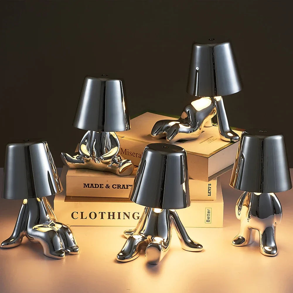 Designerska lampa stołowa LED — figurka w pozycji siedzącej, połyskujące wykończenie | Norivo Norivo