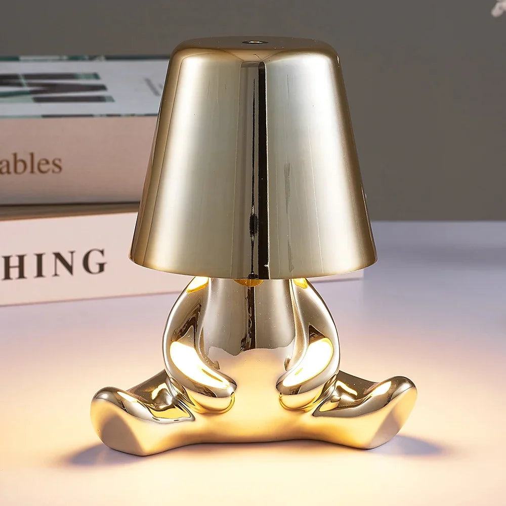 Designerska lampa stołowa LED — figurka w pozycji siedzącej, połyskujące wykończenie | Norivo Norivo