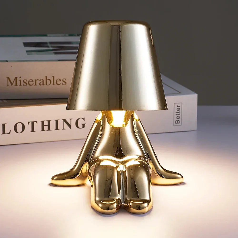 Designerska lampa stołowa LED — figurka w pozycji siedzącej, połyskujące wykończenie | Norivo Norivo