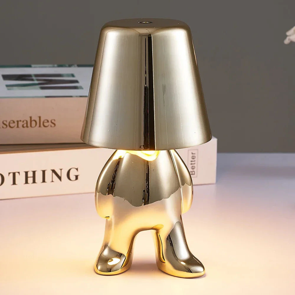 Designerska lampa stołowa LED — figurka w pozycji siedzącej, połyskujące wykończenie | Norivo Norivo