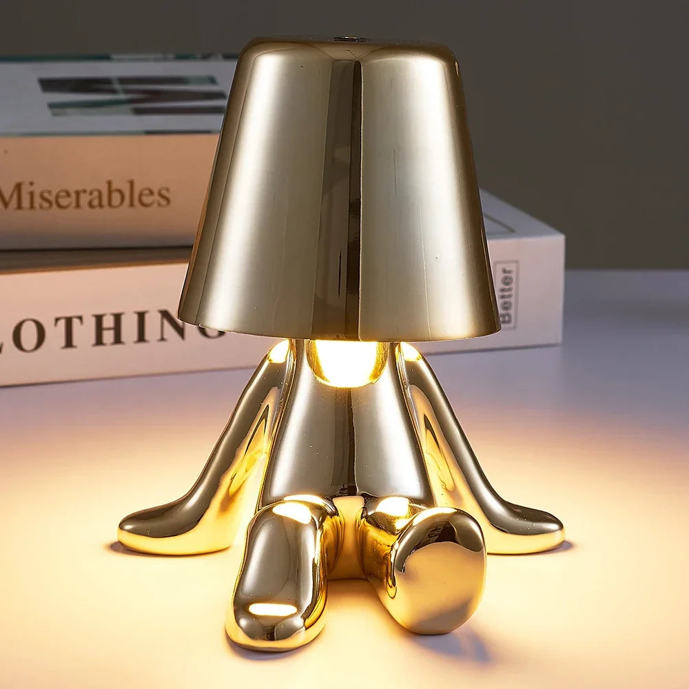 Designerska lampa stołowa LED — figurka w pozycji siedzącej, połyskujące wykończenie | Norivo Norivo