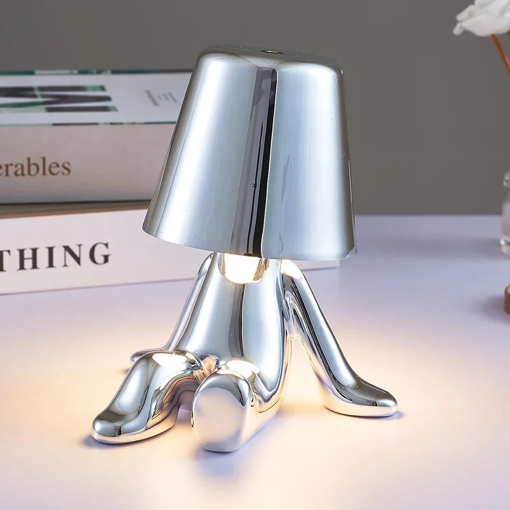 Designerska lampa stołowa LED — figurka w pozycji siedzącej, połyskujące wykończenie | Norivo Norivo