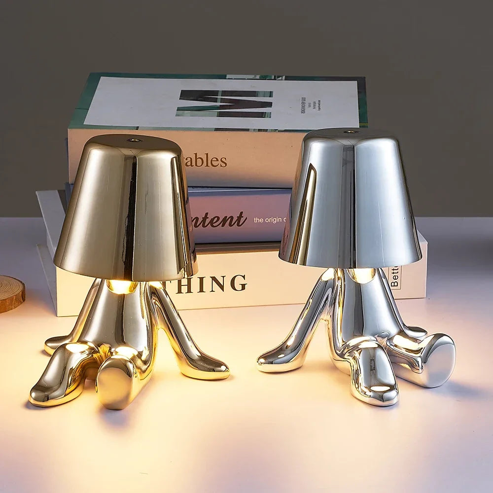 Designerska lampa stołowa LED — figurka w pozycji siedzącej, połyskujące wykończenie | Norivo Norivo
