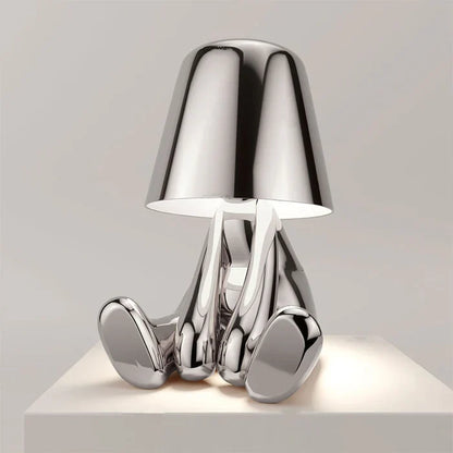 Designerska lampa stołowa LED — figurka w pozycji siedzącej, połyskujące wykończenie | Norivo Norivo